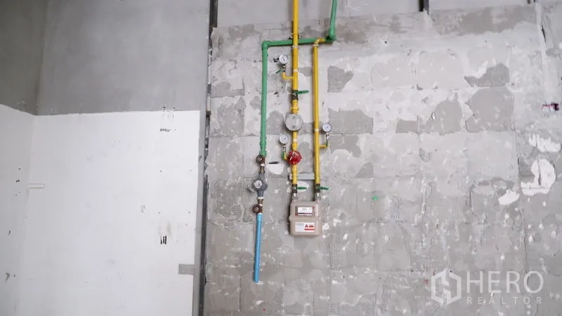 Retail Space for rent in Watthana, Bangkok - Close-up of installed gas and water meters with colored pipes on an unfinished wall.