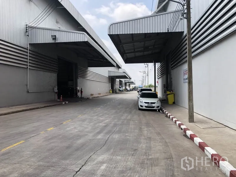 Factory for rent in Wang Noi, Phra Nakhon Si Ayutthaya - Wide access road lined with warehouses, extended canopies and parked vehicles.