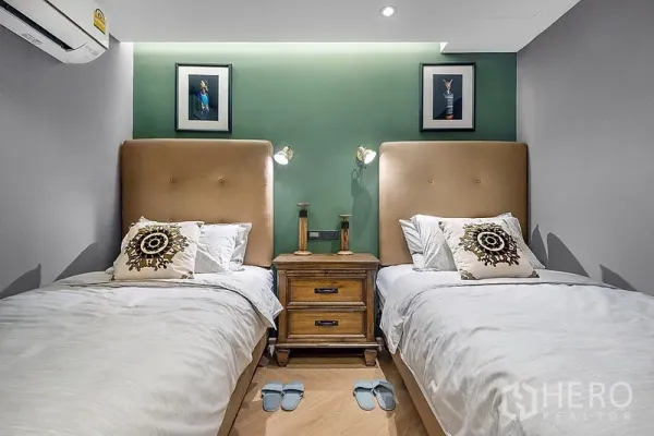 Condominium for rent in Bang Rak, Bangkok - Guest bedroom with two single beds, green accent wall, bedside table, and soft reading lights.