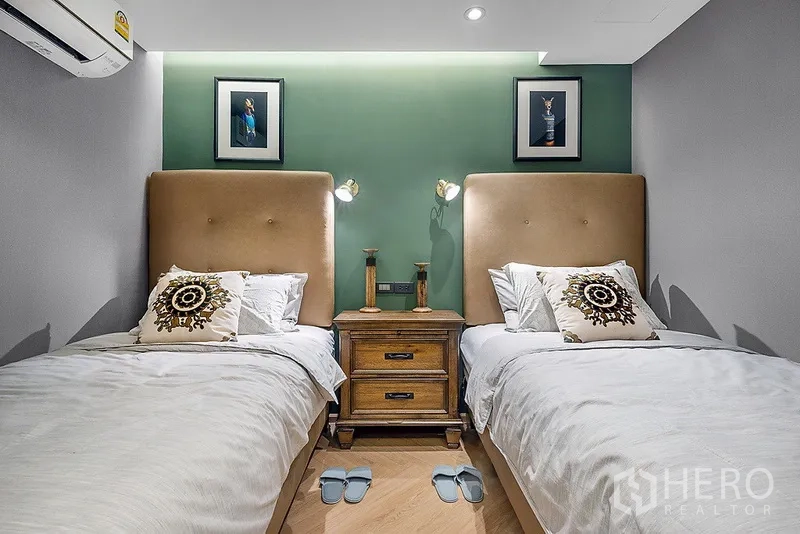 Condominium for rent in Bang Rak, Bangkok - Guest bedroom with two single beds, green accent wall, bedside table, and soft reading lights.