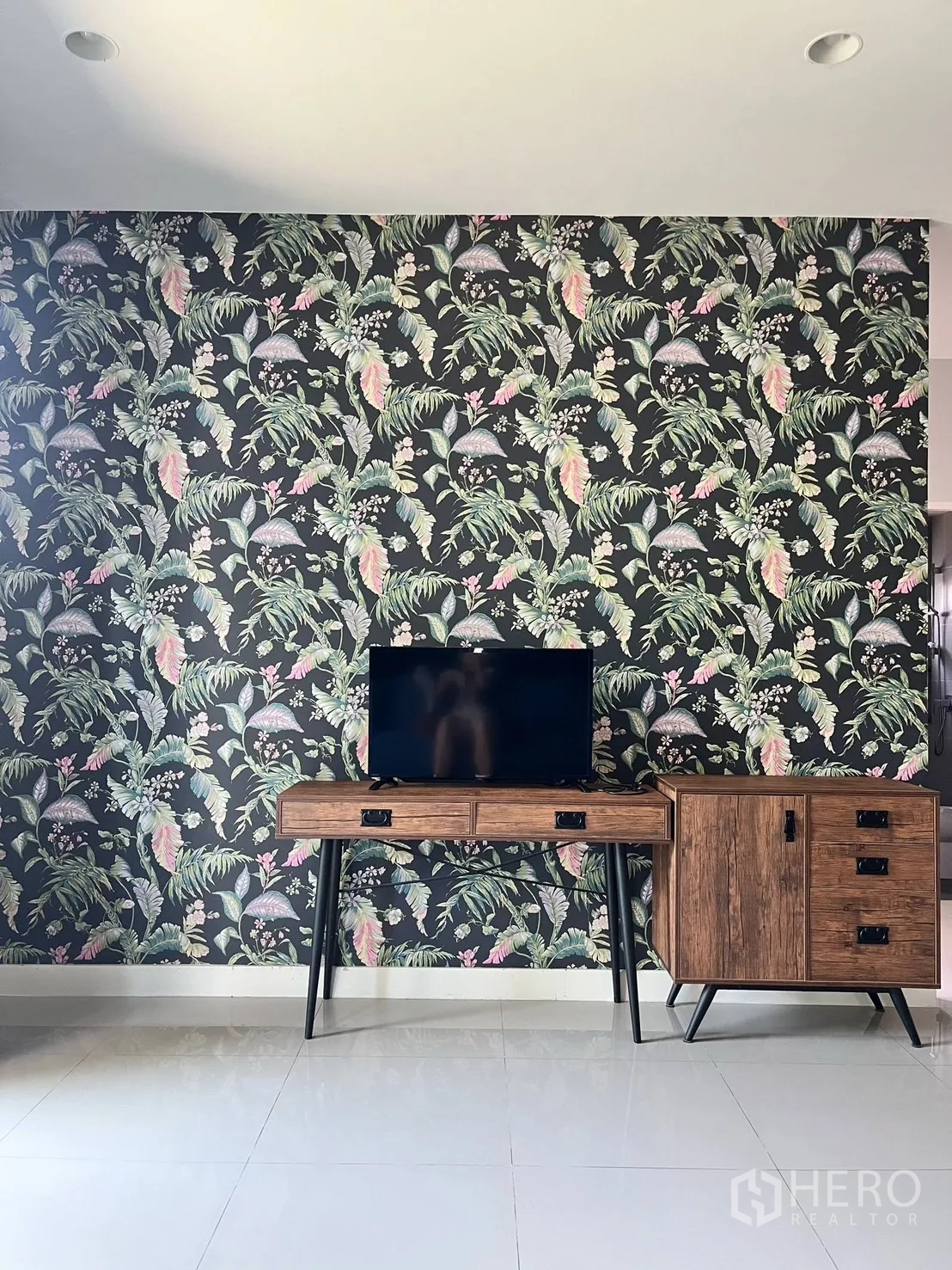 Detached House for rent or sale in Lam Luk Ka, Pathum Thani - Feature wall with tropical wallpaper and wooden TV console.