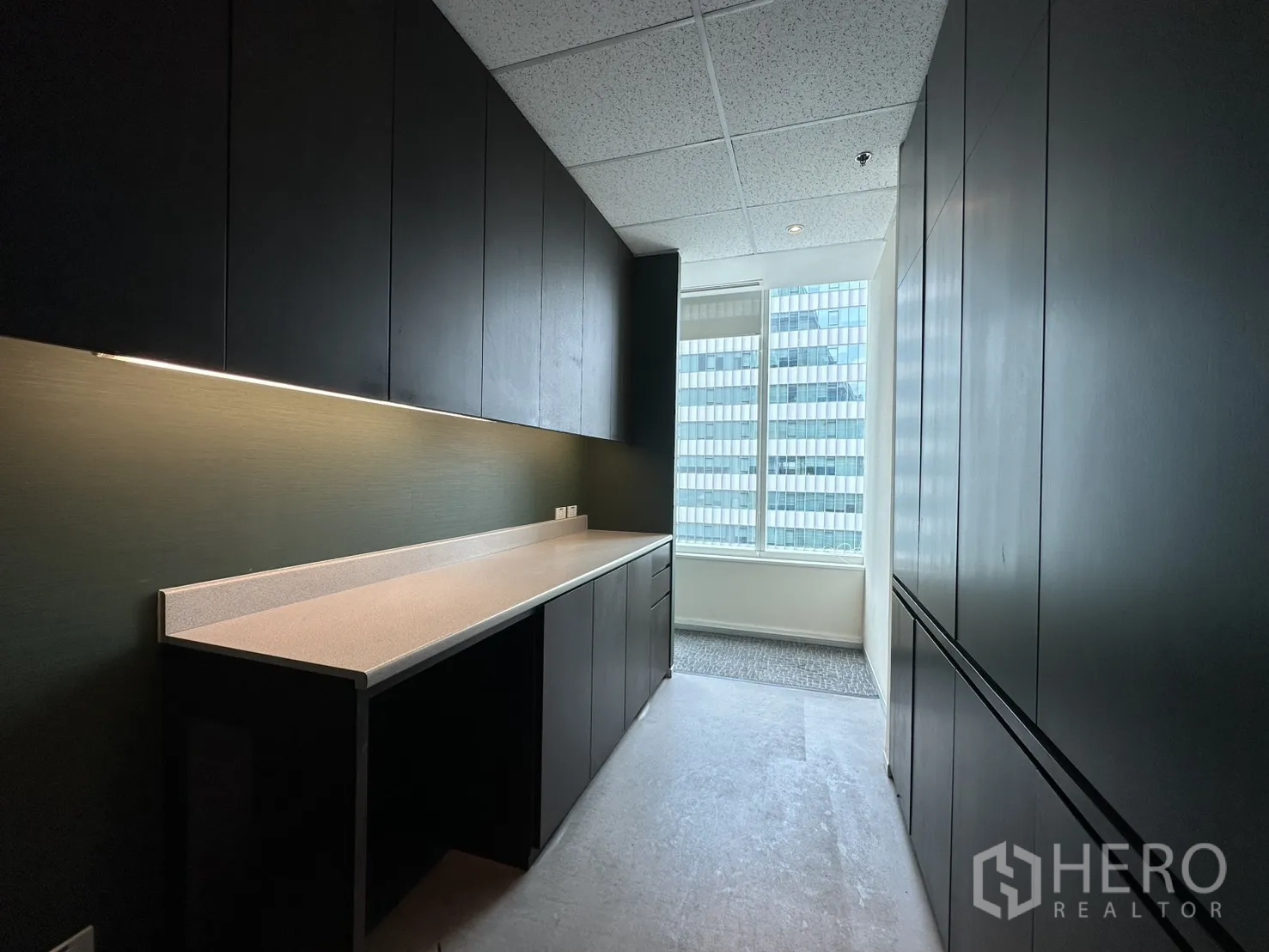 Office Space for rent in Watthana, Bangkok - Galley pantry with extensive cabinetry, task lighting, and a window at the end.