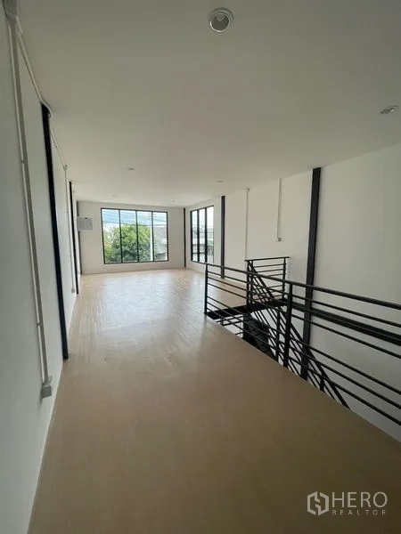 Warehouse for rent or sale in Lam Luk Ka, Pathum Thani - Upper-floor office mezzanine with metal staircase and large windows bringing in natural light.