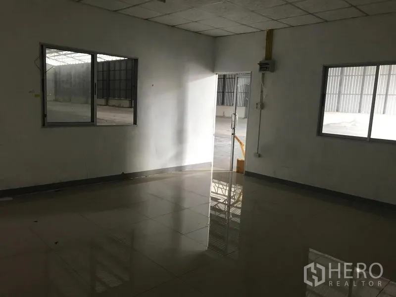 Warehouse for rent in Mueang Samut Prakan, Samut Prakan - Ground‑floor office inside the warehouse with tiled floor, windows and a glass door.