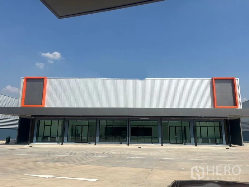 คลังสินค้า ให้เช่าในBang Phli, Samut Prakan - ด้านหน้าโกดังสมัยใหม่ พร้อมสำนักงานกระจกและกรอบสีส้ม ใต้ท้องฟ้าโปร่ง