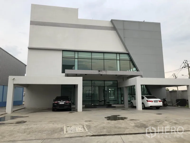 货栈 出租在Samut Prakan - 园区入口的现代玻璃幕墙办公楼外观。