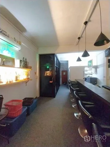 店屋 出租在Khlong Toei, Bangkok - 吧台座位、悬挂灯、玻璃隔间与发光墙架。