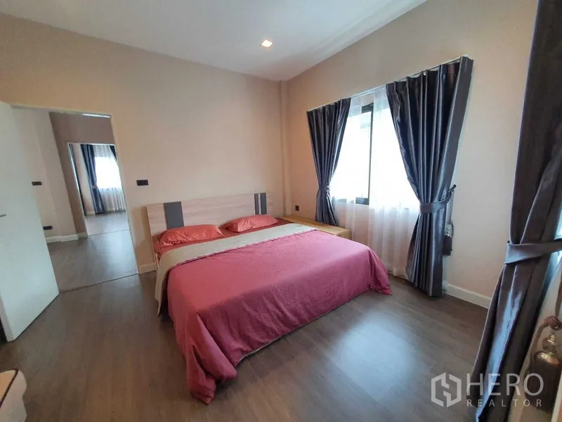 Detached House for rent in Khlong Luang, Pathum Thani - Guest bedroom with double bed, dark curtains and wood floors.