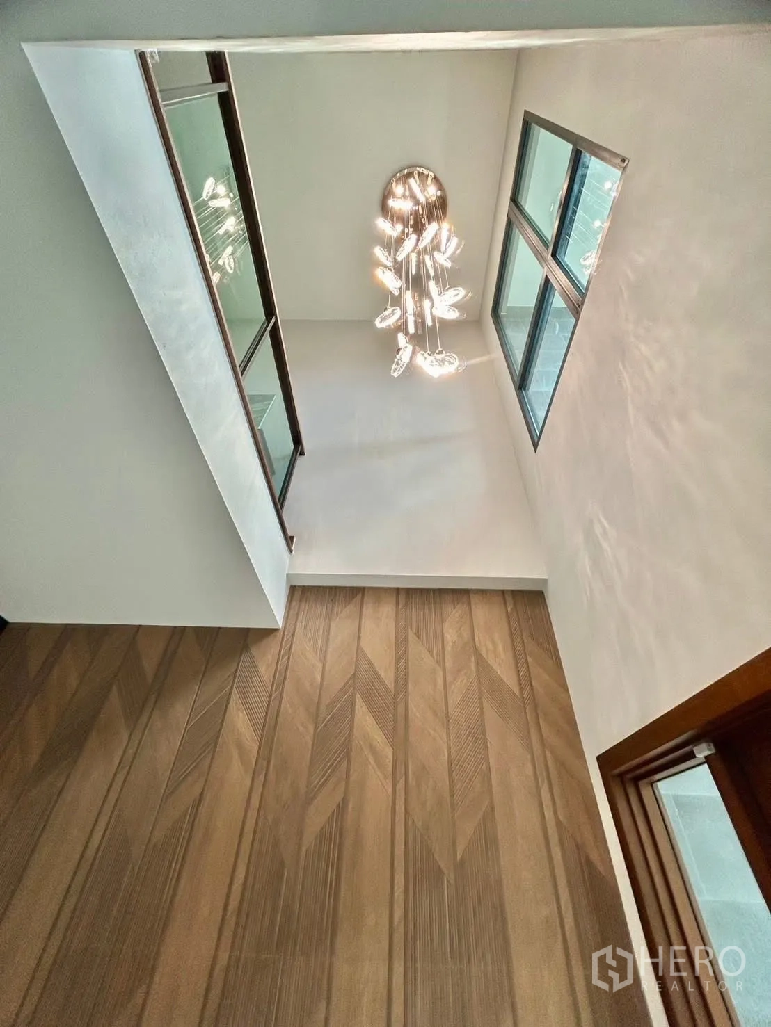 Detached House for rent in Bang Phli, Samut Prakan - Double-height stairwell with hanging crystal chandelier and glass railing.