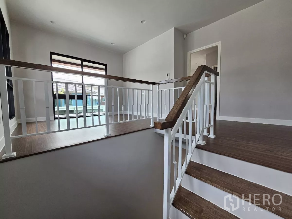 Detached House for sale in Lam Luk Ka, Pathum Thani - Stair landing with white railing and a door leading to the balcony.
