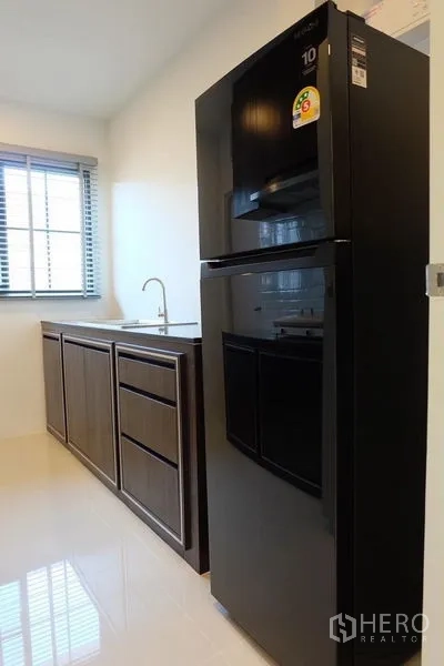 Detached House for rent in Bang Phli, Samut Prakan - Pantry area with large black refrigerator, sink, storage cabinets and window.
