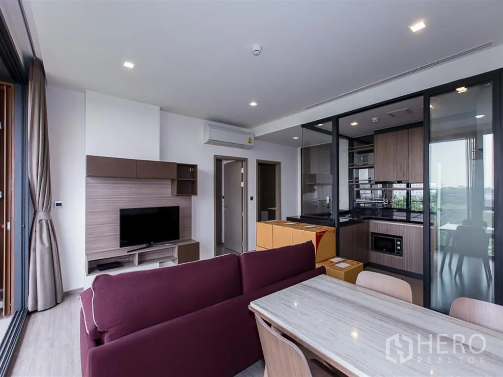 คอนโด for rent in Watthana, Bangkok - ห้องนั่งเล่นมีชั้นวางทีวี โซฟาสีม่วงแดง โต๊ะทานข้าว และครัวกั้นกระจก
