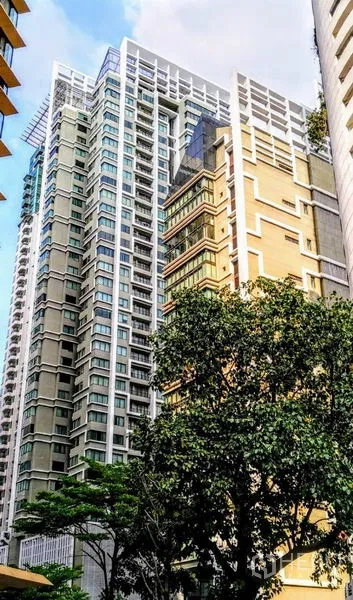 Condominium for rent in Khlong Toei, Bangkok - Modern high-rise condominium exterior with tiered facade and mature trees in foreground.
