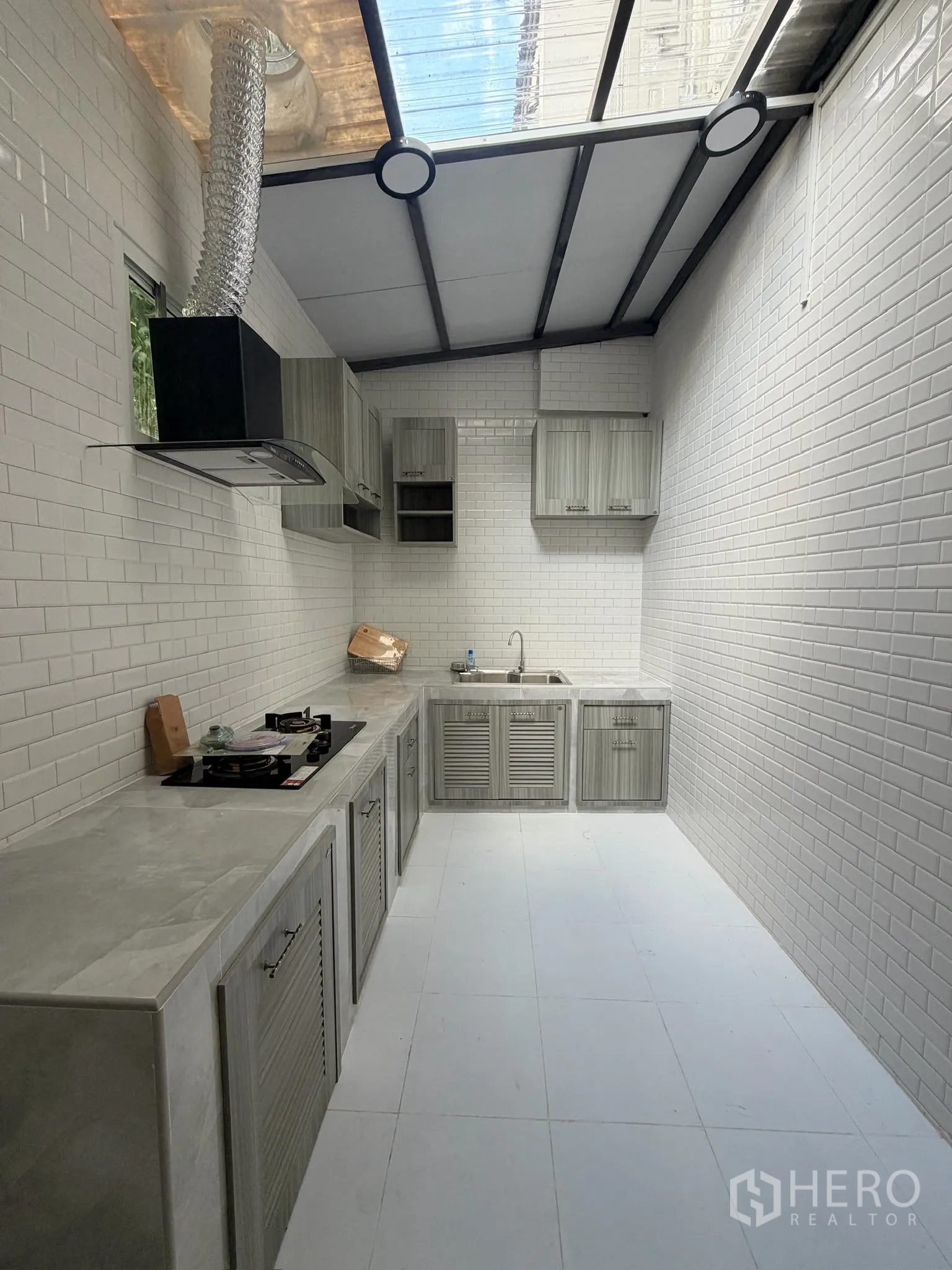 Townhouse for rent or sale in Yan Nawa, Bangkok - Covered kitchen with white subway tiles, grey cabinets, and gas stove.