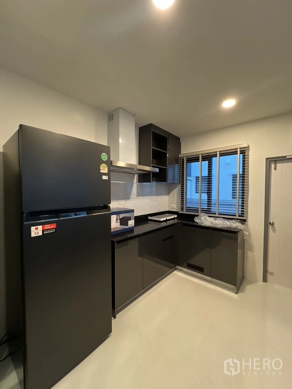 Detached House for rent in Bang Phli, Samut Prakan - Modern kitchen with black cabinetry, refrigerator and range hood.