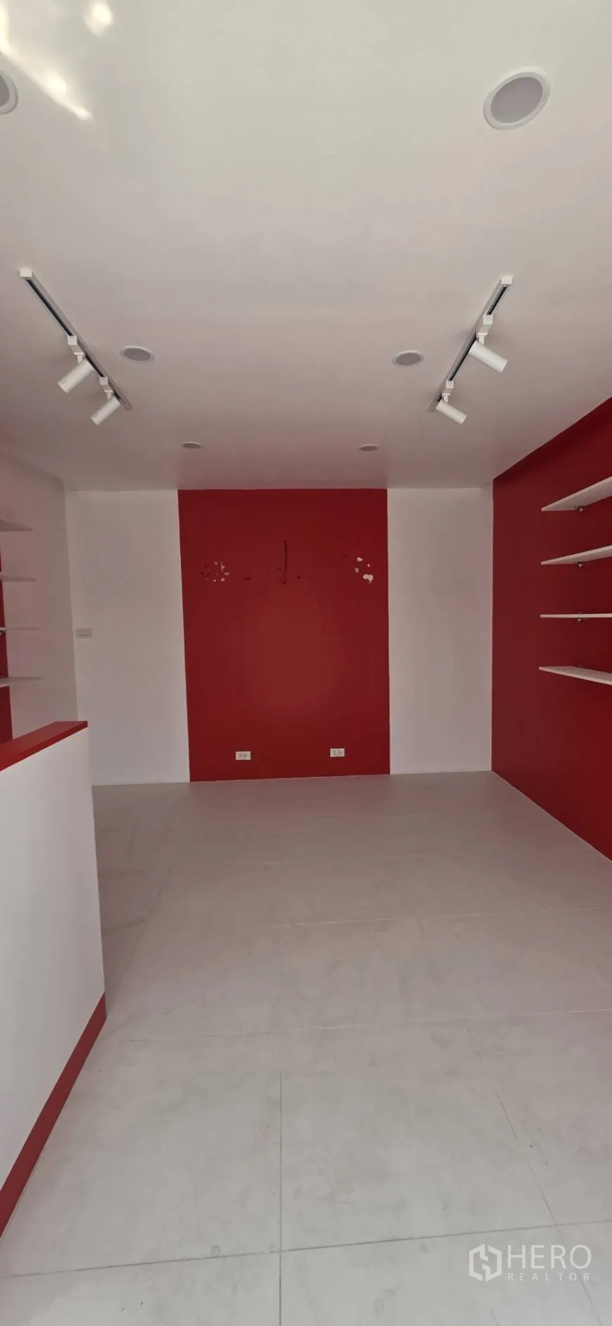 零售空间 for rent in Watthana, Bangkok - 店铺纵深视角，浅色地砖、红色背景墙与天花射灯。