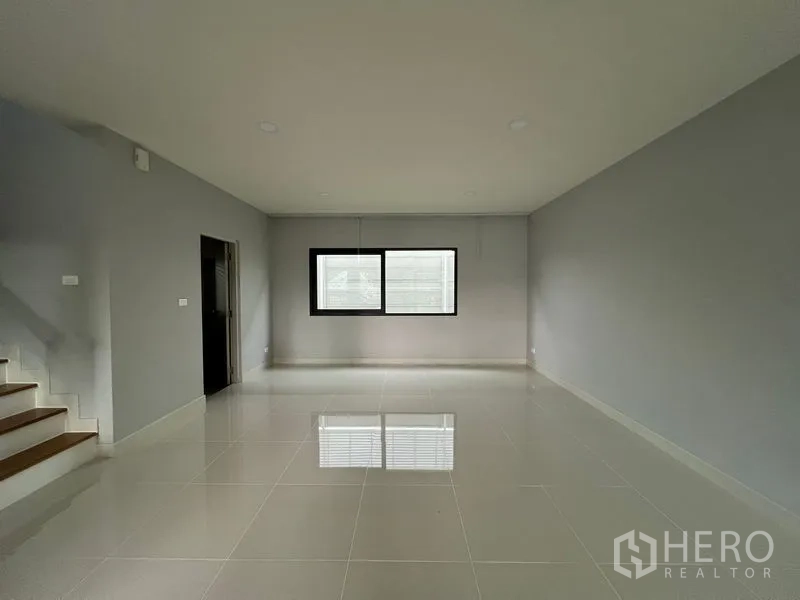 Detached House for rent or sale in Bang Phli, Samut Prakan - Bright empty room with glossy tile floor and staircase on the side.