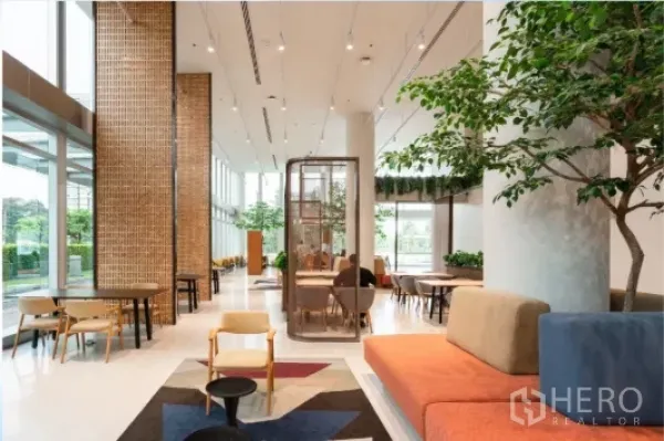 Office Space for rent in Chatuchak, Bangkok - Ground-floor social space with cafe-style seating and indoor trees by tall windows.
