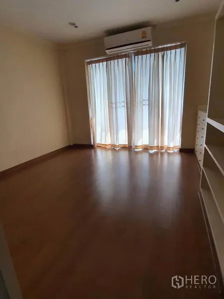 Townhouse for rent in Huai Khwang, Bangkok - Bedroom with wood floors, balcony doors and wall-mounted air conditioner.