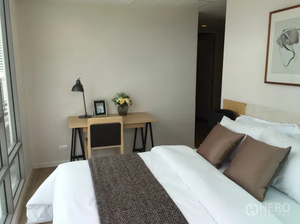 Condominium for sale in Bang Rak, Bangkok - Bright master bedroom with a work desk by large windows and a city view.
