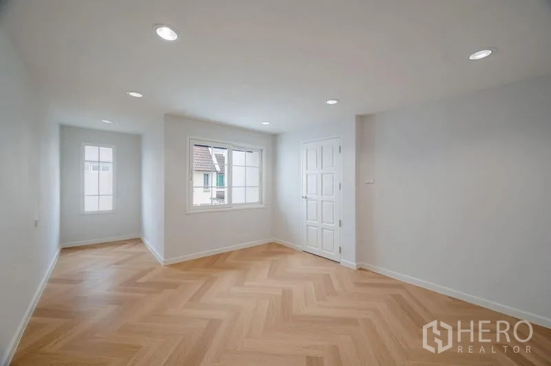 Townhouse for sale - Open multipurpose room with herringbone wood floor, recessed lights and bright windows.