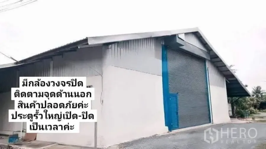 Warehouse for rent in Nakhon Pathom - Modern warehouse facade featuring a large blue roller shutter door and pitched roof.