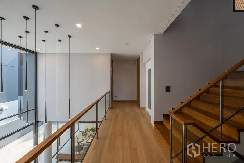 Detached House for rent or sale in Yan Nawa, Bangkok - Upper hallway with glass balustrade, wood floors and hanging pendant lights.
