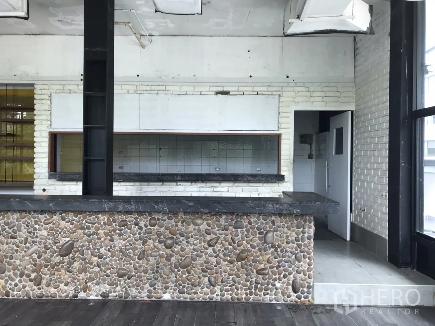 Retail Space for rent in Khlong Toei, Bangkok - Interior bar counter with stone cladding, serving hatch and industrial ceiling.