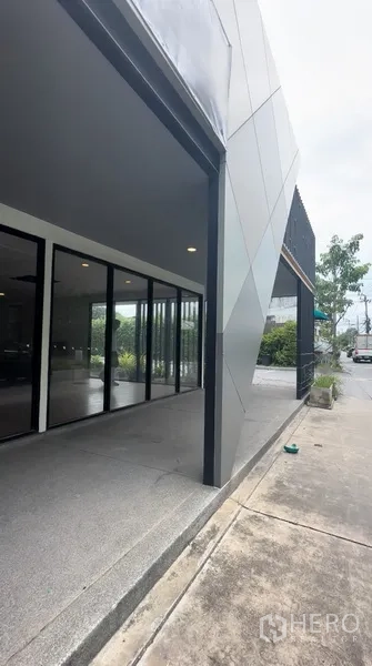 零售空间 出租在Bang Na, Bangkok - 临街带顶入口走道，落地玻璃与斜面金属板形成醒目门面。