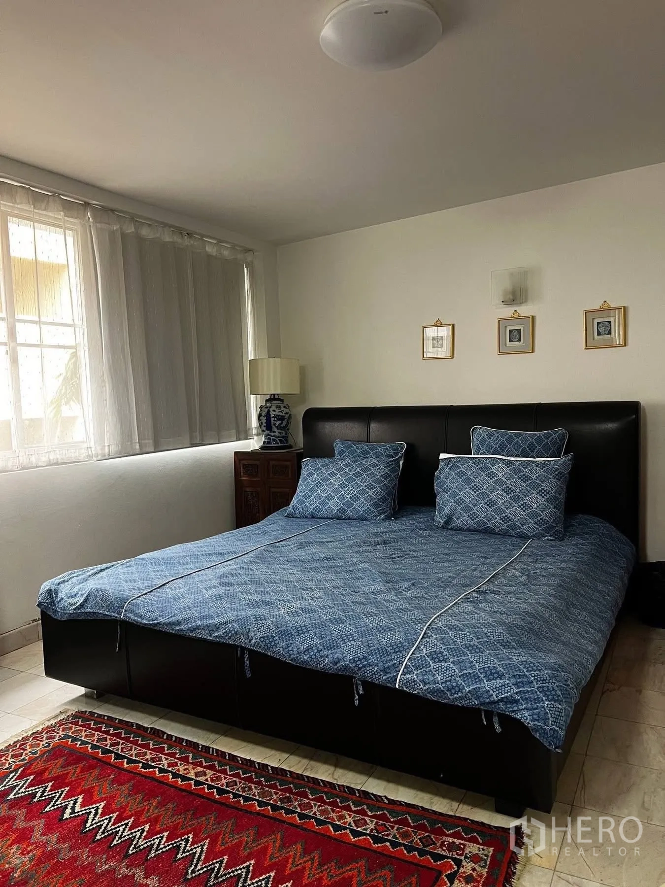 联排别墅 for rent or sale in Watthana, Bangkok - 卧室设大窗、双人床与彩色地毯。