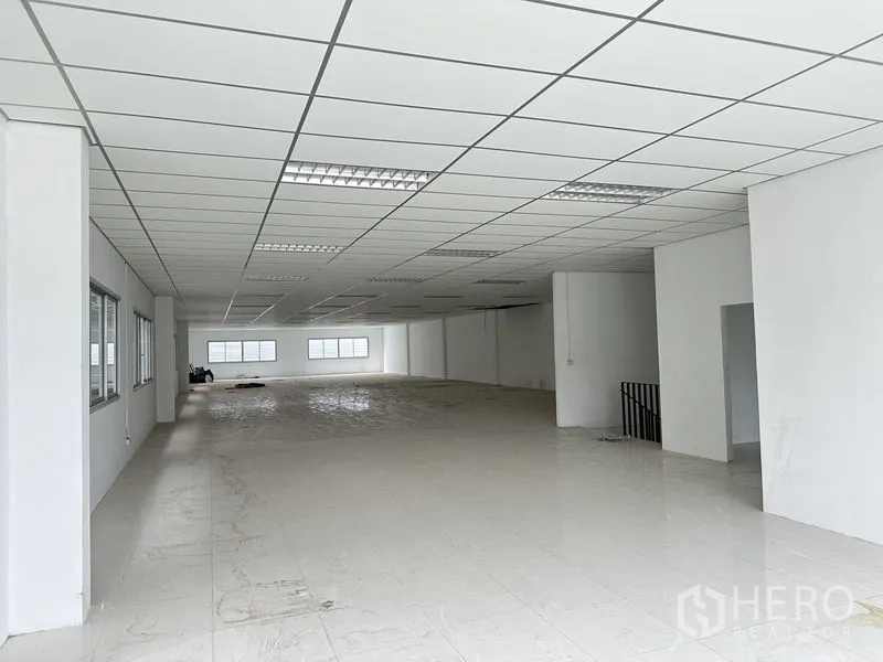 Factory for rent in Pathum Thani - Spacious white office floor with grid ceiling lights and windows inside the factory.