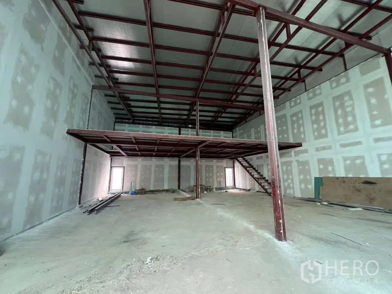 Retail Space for rent in Watthana, Bangkok - Double-height retail shell with steel mezzanine and staircase inside.