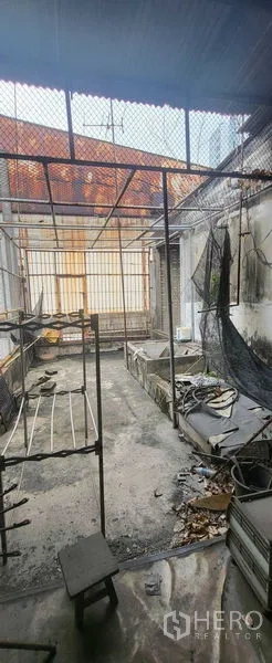 Shophouse for rent in Khlong Toei, Bangkok - Rear utility terrace with metal mesh roof and urban backdrop.