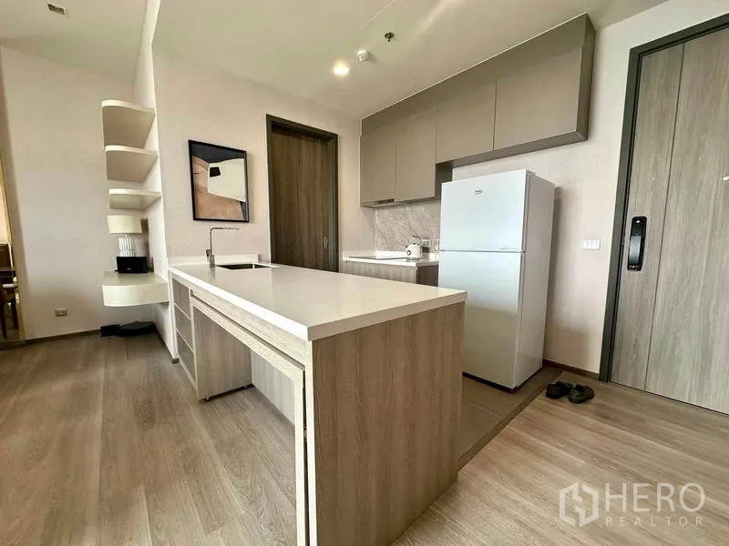 Condominium for rent in Bang Kho Laem, Bangkok - Modern kitchen with large island, white countertops, light wood cabinetry and a full-size refrigerator.