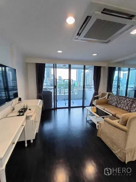 Condominium for rent in Watthana, Bangkok - Living area facing wide glass doors to balcony and skyline.