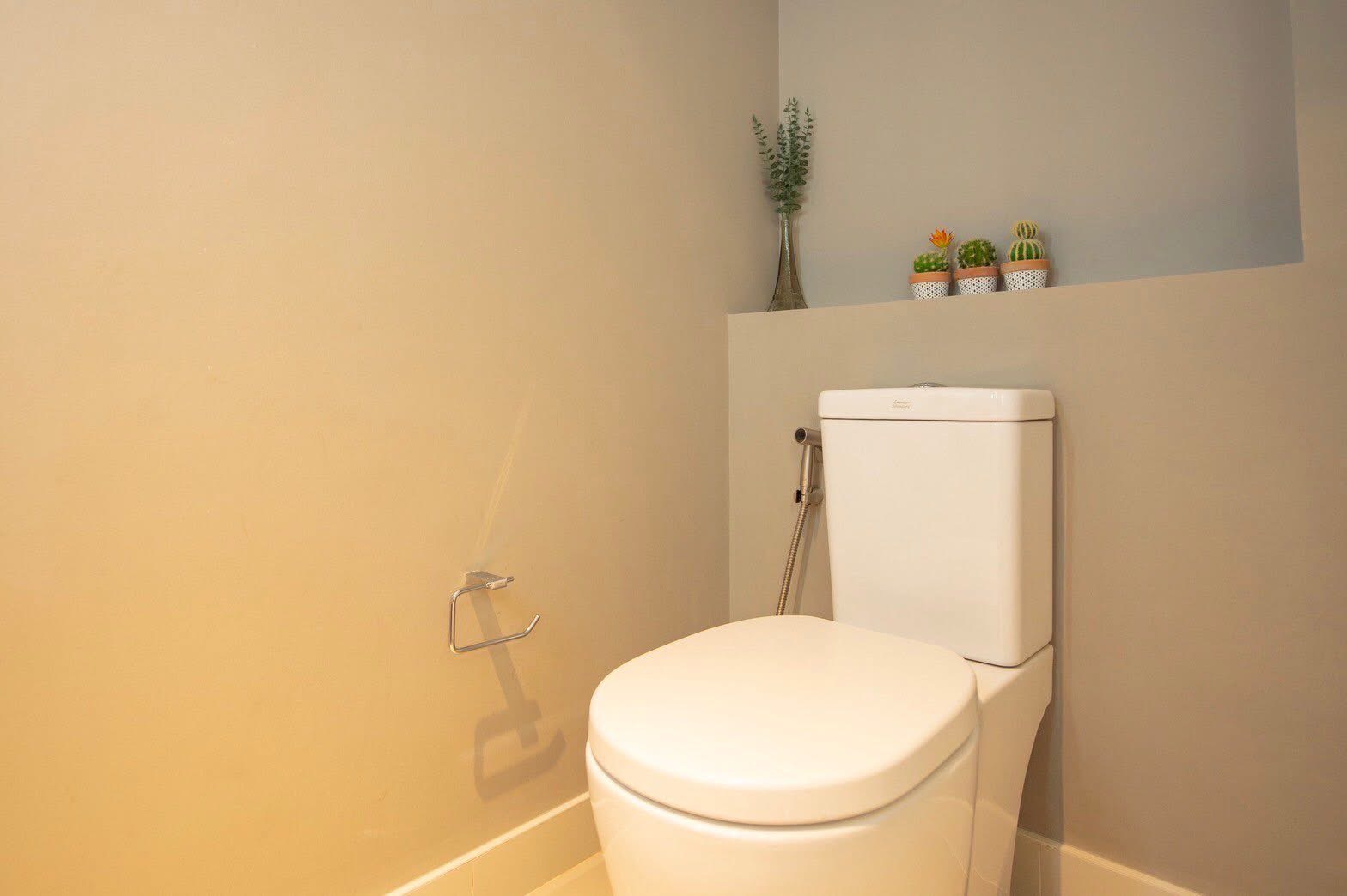 Townhouse for rent or sale in Lat Phrao, Bangkok - Minimalist guest toilet with white WC and decorative plants on a wall niche.