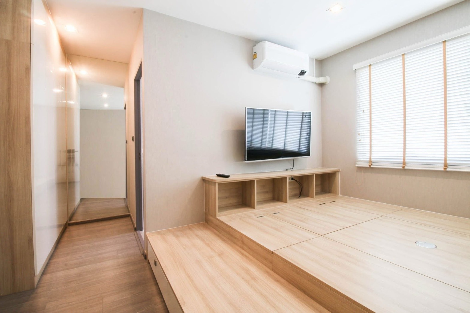 Townhouse for rent or sale in Lat Phrao, Bangkok - Raised tatami-style media room with wall-mounted TV, built-in storage and window blinds.