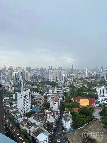 Condominium for rent or sale in Khlong Toei, Bangkok - High-floor panoramic view of Bangkok city with mid- and high-rise buildings and green pockets.