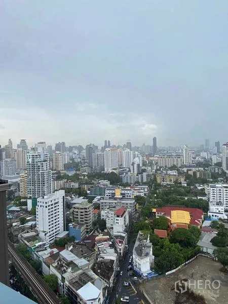 Condominium for rent or sale in Khlong Toei, Bangkok - High-floor panoramic view of Bangkok city with mid- and high-rise buildings and green pockets.