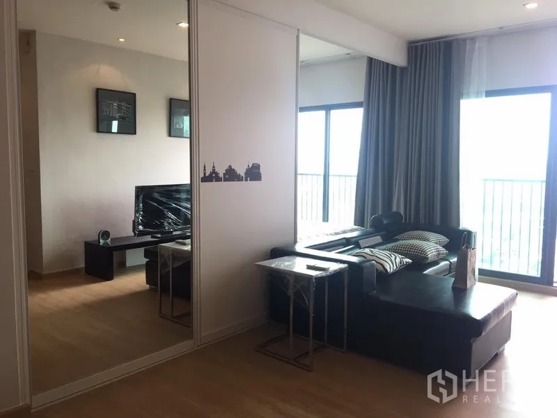 公寓 出租在Khlong Toei, Bangkok - 开放式客厅，L形皮沙发，镜面推拉门与两扇阳台门，采光良好。