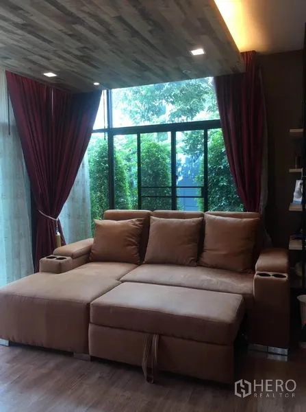 独立式住宅 出售在Pak Kret, Nonthaburi - 舒适起居角落，大号棕色沙发靠落地窗而设。
