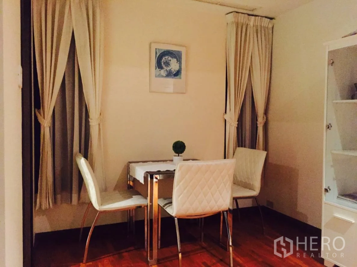Condominium for rent in Sathon, Bangkok - Cozy dining nook with four white quilted chairs, small table and floor‑to‑ceiling curtains.