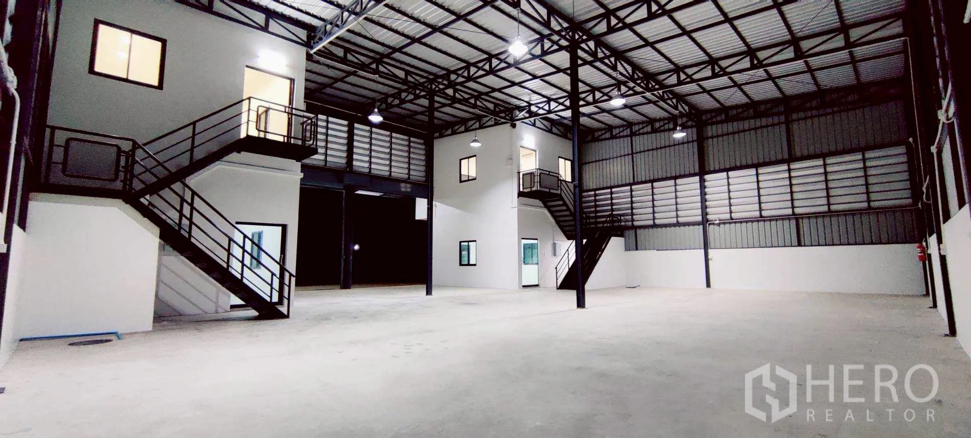 Warehouse for rent in Lam Luk Ka, Pathum Thani - Open storage space with two staircases leading to upstairs offices and catwalk.