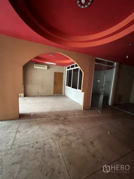 Shophouse for rent in Watthana, Bangkok - Open-plan room with archway, red feature ceiling and a glass cubicle.