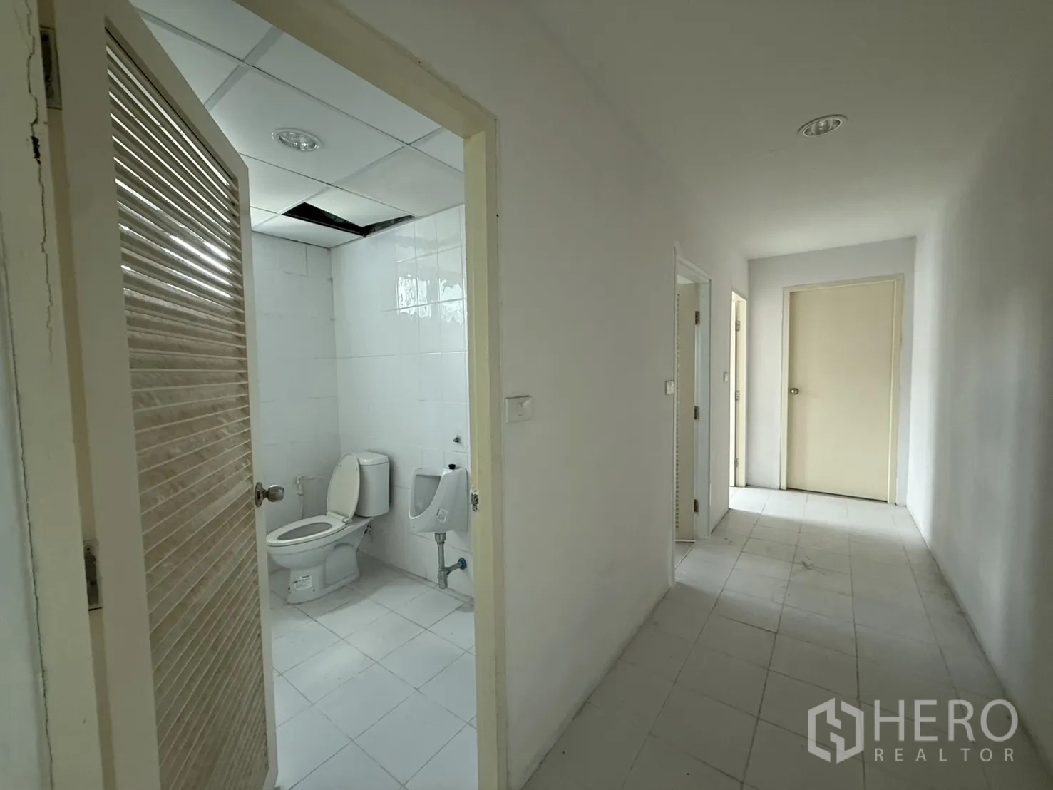 办公空间 出租在Bueng Kum, Bangkok - 干净的瓷砖卫生间，配坐便器与小便池，连通走廊