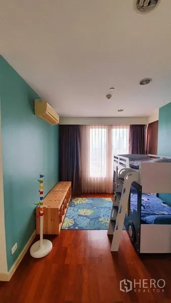 Condominium for rent in Watthana, Bangkok - Children’s bedroom with bunk bed, teal walls, wood flooring and balcony‑style doors.