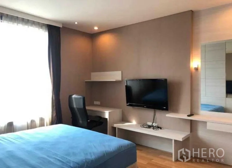 Condominium for sale in Khlong Toei, Bangkok - Open-plan living room with chandelier, sofa and kitchen island seating.
