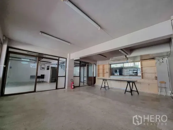Office Space for rent in Din Daeng, Bangkok - Large workspace featuring glass walls, built-in shelving, a long workbench, air conditioning and fluorescent lighting.