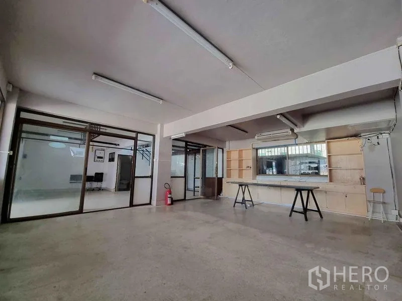 Office Space for rent in Din Daeng, Bangkok - Large workspace featuring glass walls, built-in shelving, a long workbench, air conditioning and fluorescent lighting.