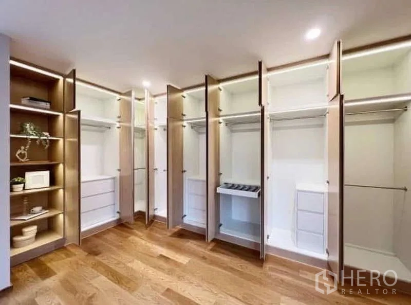 Townhouse for rent or sale in Saphan Sung, Bangkok - Walk-in closet with doors open showing hanging rails, drawers and shelves.
